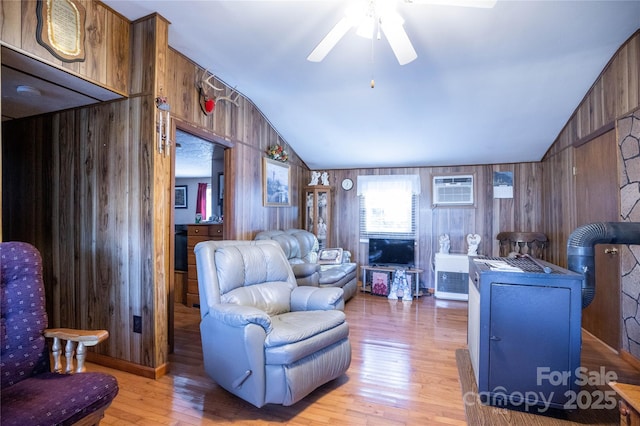 living room featuring lofted ceiling, ceiling fan, wood walls, a wall unit AC, and light wood-type flooring