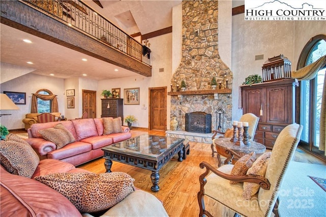 living room featuring light hardwood / wood-style flooring, a towering ceiling, and a fireplace