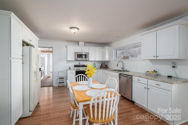 kitchen with white cabinets, light hardwood / wood-style floors, appliances with stainless steel finishes, and light stone countertops