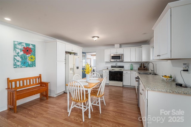 kitchen with white cabinetry, light wood-type flooring, appliances with stainless steel finishes, and sink