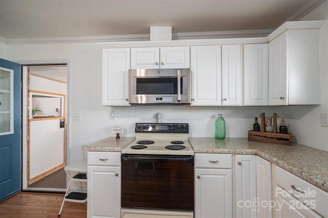 kitchen with electric stove, white cabinetry, and wood-type flooring