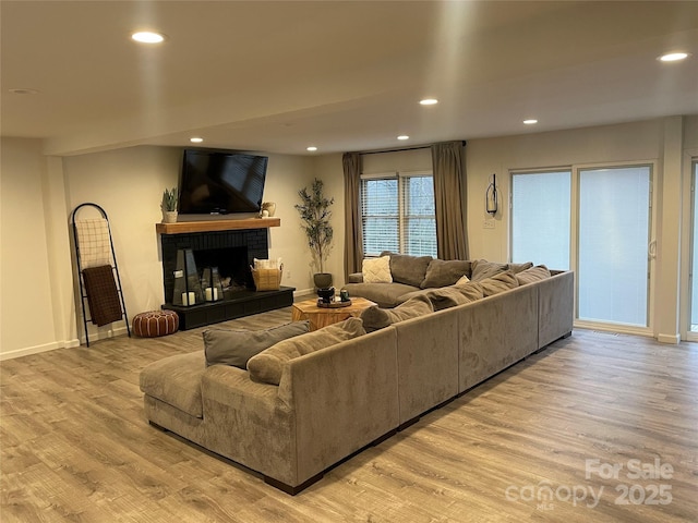 living room featuring a brick fireplace and light wood-type flooring