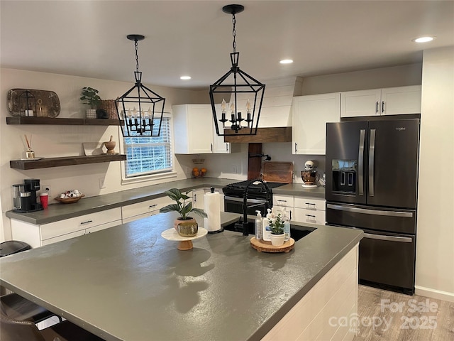 kitchen with pendant lighting, white cabinets, black fridge with ice dispenser, and light hardwood / wood-style floors