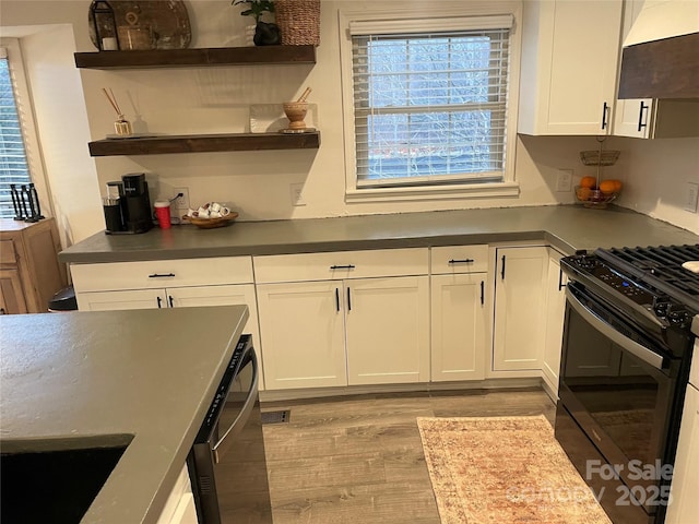 kitchen featuring white cabinetry, extractor fan, light hardwood / wood-style flooring, and black appliances