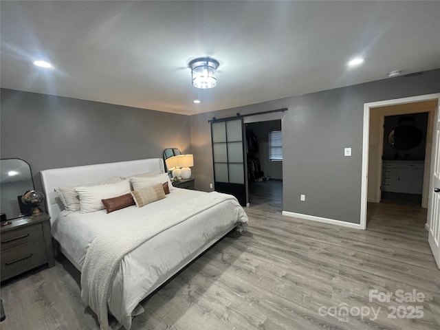 bedroom featuring a barn door and light hardwood / wood-style floors