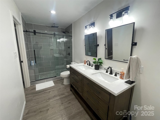 bathroom with an enclosed shower, vanity, wood-type flooring, and toilet