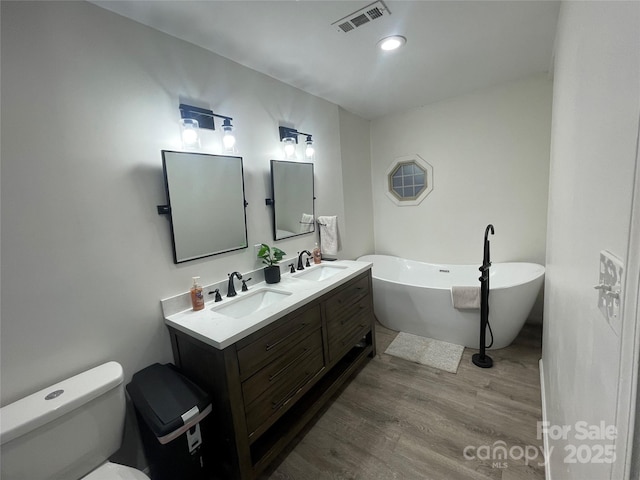 bathroom featuring vanity, wood-type flooring, a tub, and toilet