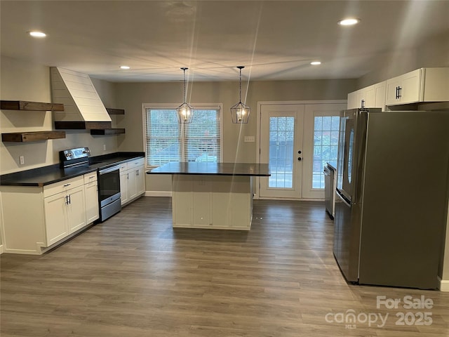 kitchen featuring a kitchen island, appliances with stainless steel finishes, hanging light fixtures, and white cabinets