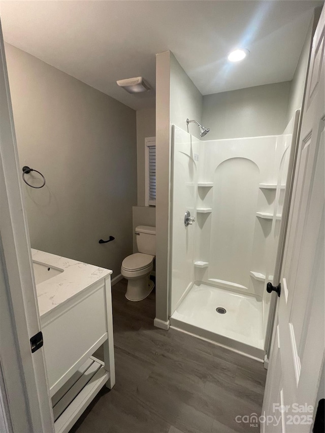 bathroom featuring hardwood / wood-style flooring, vanity, toilet, and walk in shower