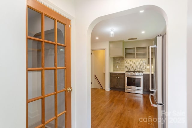 kitchen featuring appliances with stainless steel finishes, light hardwood / wood-style flooring, green cabinets, and decorative backsplash