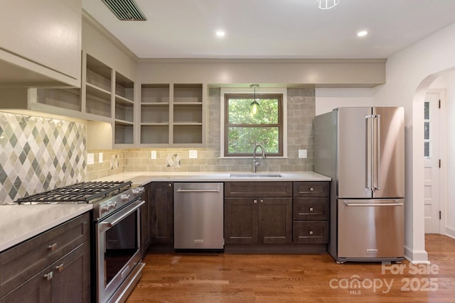 kitchen with dark hardwood / wood-style flooring, premium appliances, dark brown cabinets, and sink