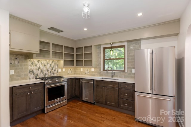 kitchen with dark brown cabinetry, sink, high end appliances, dark hardwood / wood-style flooring, and backsplash