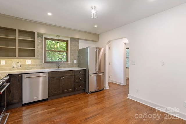 kitchen featuring sink, appliances with stainless steel finishes, dark brown cabinetry, tasteful backsplash, and light hardwood / wood-style floors