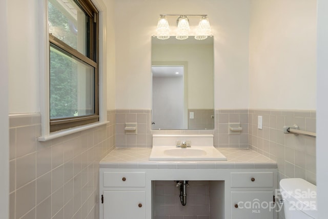 bathroom featuring vanity, toilet, and tile walls