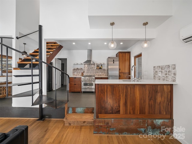 kitchen featuring kitchen peninsula, appliances with stainless steel finishes, backsplash, wall chimney exhaust hood, and sink