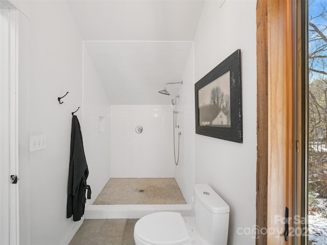 bathroom featuring toilet, tile patterned flooring, and a tile shower