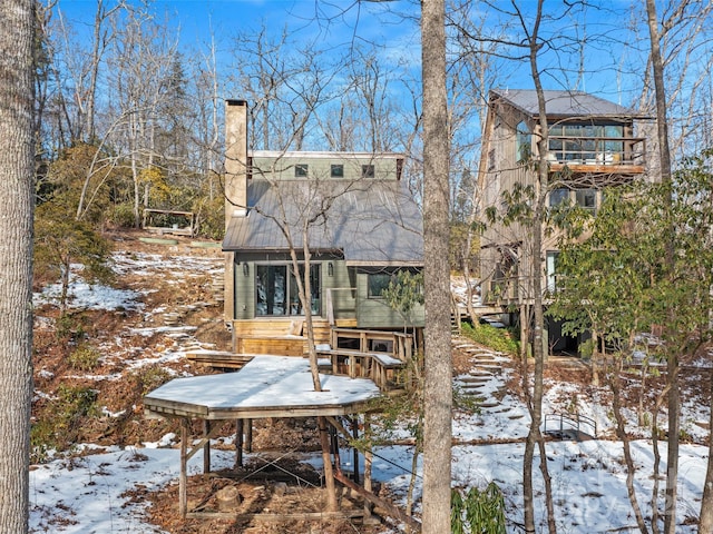 snow covered back of property with a sunroom