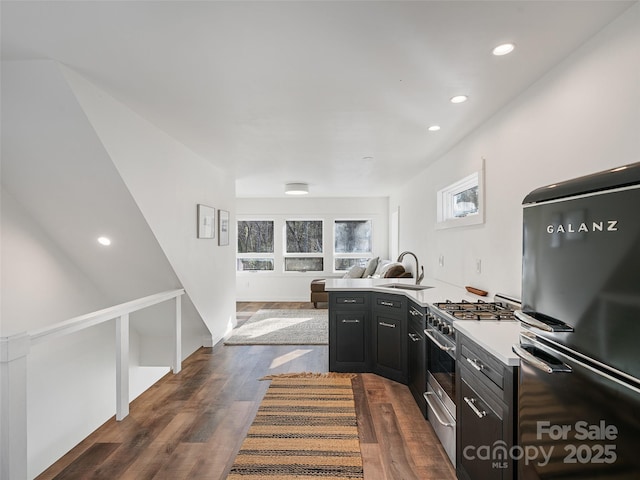 kitchen featuring high end stainless steel range, black refrigerator, dark hardwood / wood-style flooring, sink, and kitchen peninsula