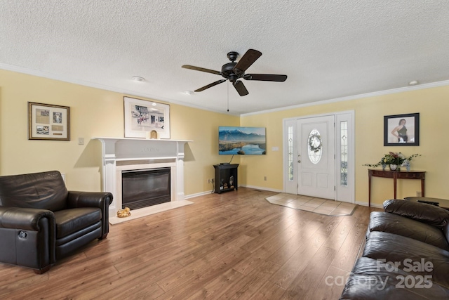 living room featuring ornamental molding, hardwood / wood-style floors, ceiling fan, and a textured ceiling