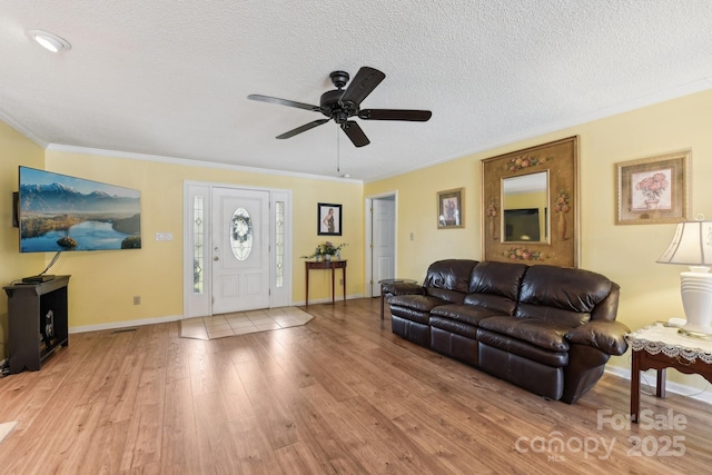 living room with crown molding, ceiling fan, light hardwood / wood-style floors, and a textured ceiling