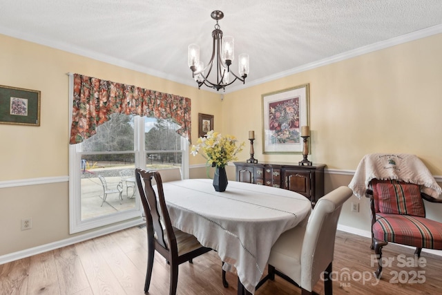 dining area with a notable chandelier, ornamental molding, and light wood-type flooring