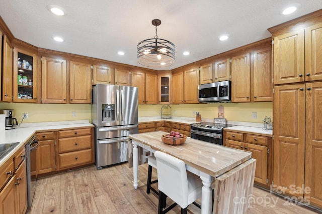 kitchen with decorative light fixtures, butcher block counters, a center island, light hardwood / wood-style floors, and stainless steel appliances