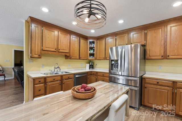 kitchen with sink, light hardwood / wood-style flooring, wooden counters, stainless steel appliances, and a textured ceiling