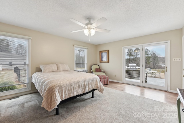 bedroom featuring ceiling fan, access to exterior, a textured ceiling, and light hardwood / wood-style flooring