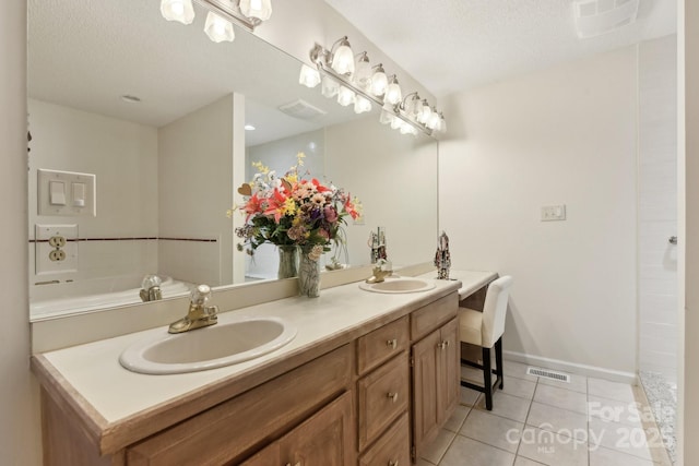 bathroom with tile patterned floors, a bathing tub, a textured ceiling, and vanity