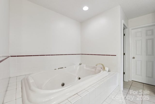 bathroom featuring tile patterned flooring, tiled bath, and a textured ceiling