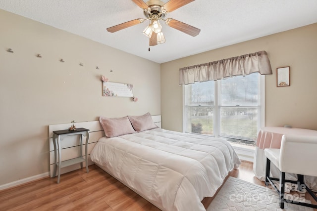 bedroom with ceiling fan, light hardwood / wood-style flooring, and a textured ceiling