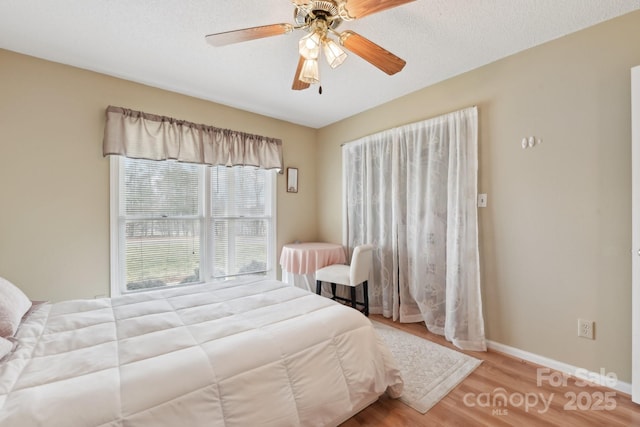 bedroom featuring ceiling fan, light hardwood / wood-style flooring, and a textured ceiling