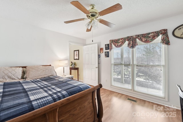 bedroom featuring hardwood / wood-style flooring, ceiling fan, and a textured ceiling