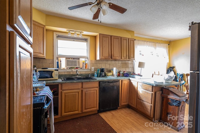 kitchen featuring sink, stainless steel refrigerator, black dishwasher, light hardwood / wood-style floors, and decorative backsplash