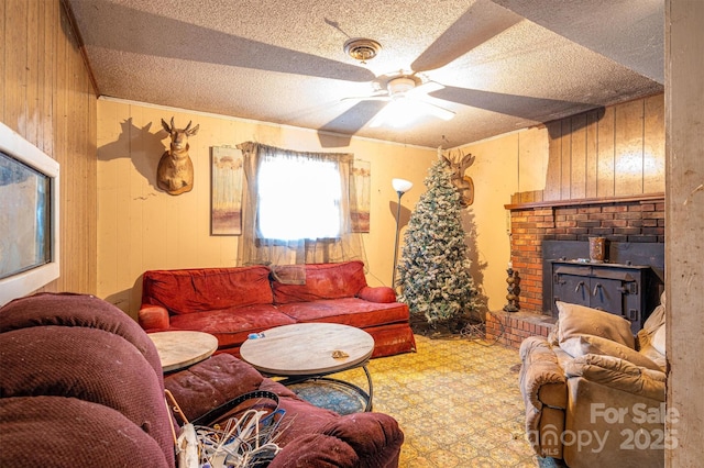 living room with ceiling fan, wooden walls, and a textured ceiling