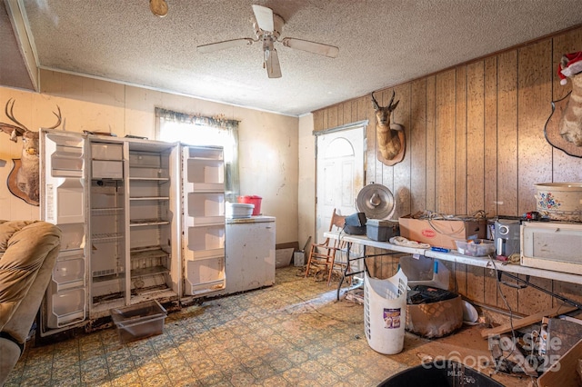 kitchen featuring ceiling fan, a textured ceiling, and wood walls