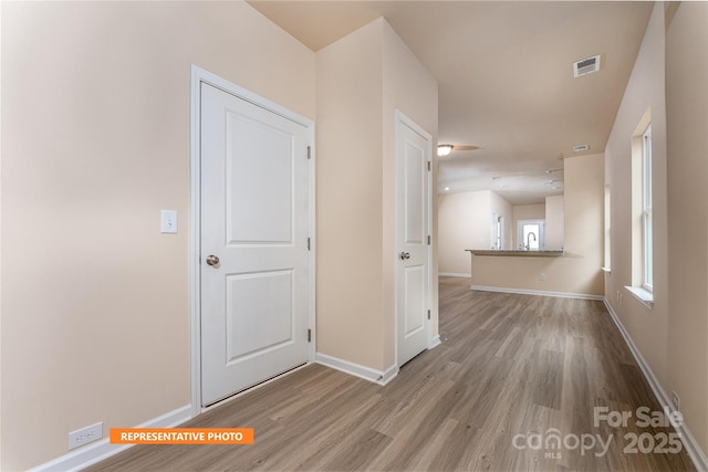spare room with wood finished floors, a sink, baseboards, and visible vents
