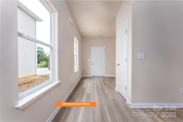hall featuring light wood-style flooring and baseboards