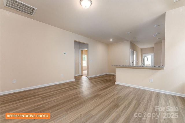 empty room featuring visible vents, baseboards, and light wood-style flooring