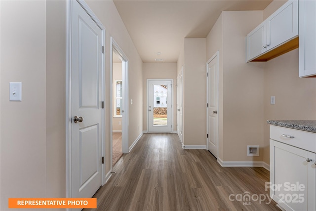 hallway featuring dark wood-type flooring and baseboards