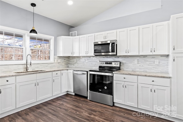 kitchen featuring sink, vaulted ceiling, appliances with stainless steel finishes, decorative backsplash, and white cabinets