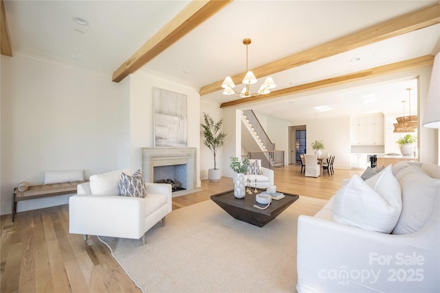 living room with a notable chandelier, beam ceiling, and light hardwood / wood-style flooring