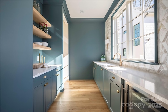 bar with sink, a wealth of natural light, backsplash, and light hardwood / wood-style flooring