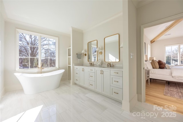 bathroom featuring ornamental molding, vanity, and a bath