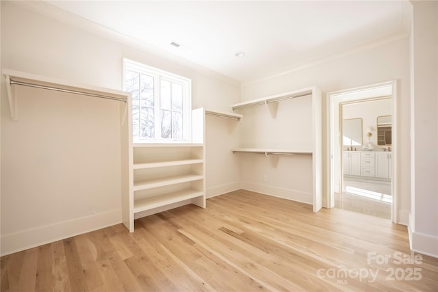 walk in closet with light hardwood / wood-style flooring