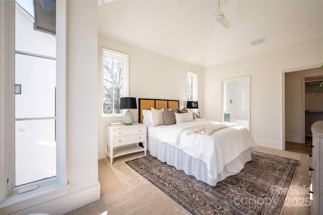 bedroom with ceiling fan, light colored carpet, lofted ceiling, and ensuite bathroom