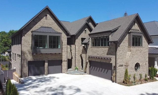 view of front of home featuring a standing seam roof, brick siding, an attached garage, and driveway