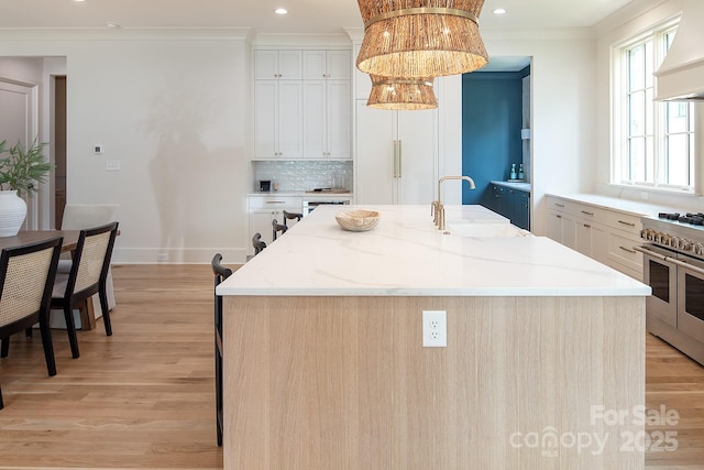 1214 S Kings Dr Unit A, Charlotte, NC 28207 - kitchen with range with two ovens, custom range hood, light wood finished floors, a kitchen island with sink, and crown molding