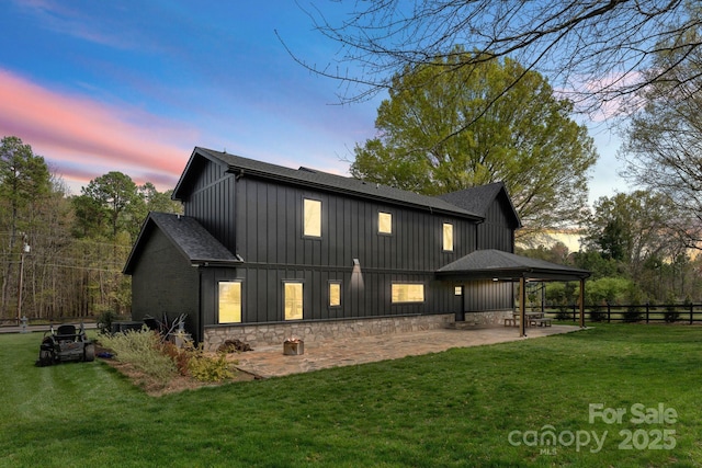 back house at dusk with a yard and a patio