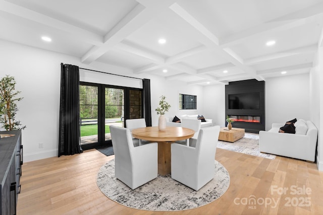 dining room with a large fireplace, coffered ceiling, beam ceiling, and light wood-type flooring